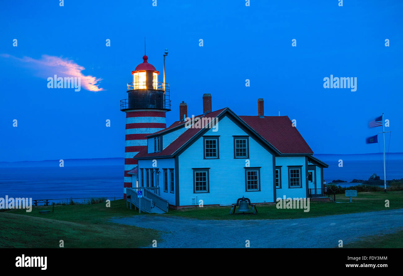 Lubec, Maine: West Quoddy Head Light in serata con la luce dal sorgere della luna scintillante tra le nuvole Foto Stock