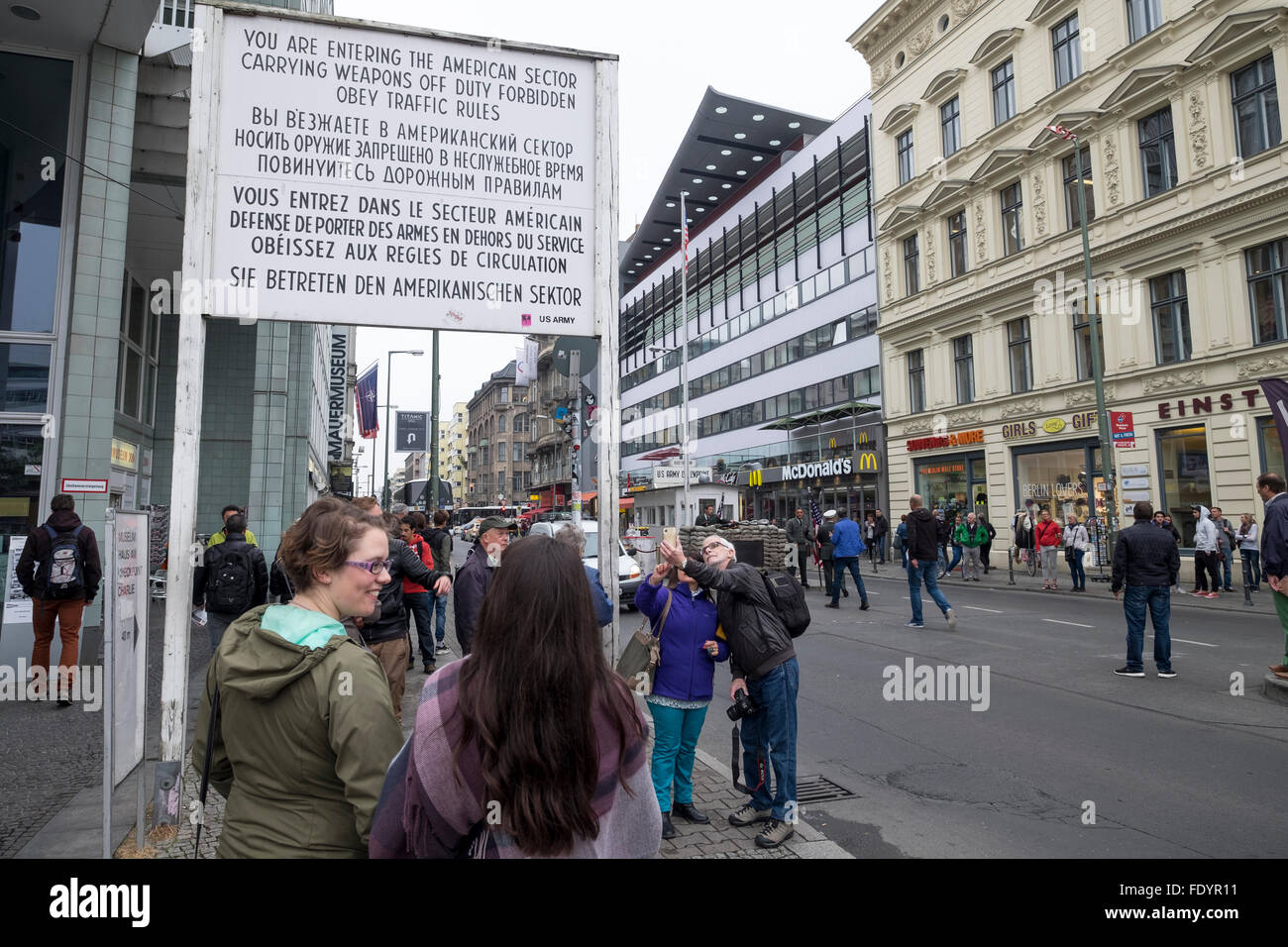 I turisti a "Checkpoint Charlie" Berlino vicino il segno di informare le persone che stanno entrando in settore americano. Foto Stock