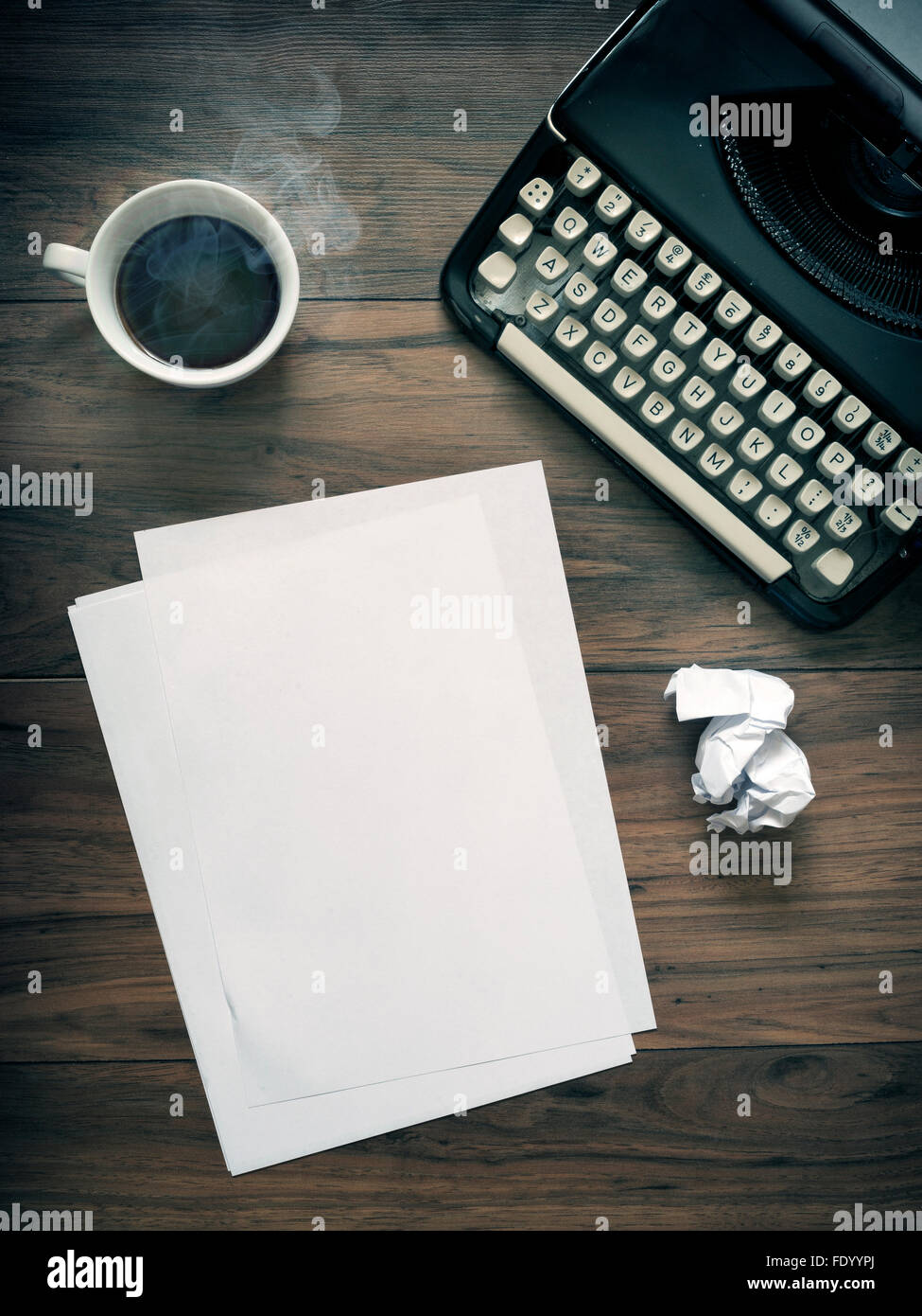 Una macchina da scrivere Vintage su una tavola di legno con il caffè e la carta. Vintage lo spazio in ufficio. carta bianca Foto Stock