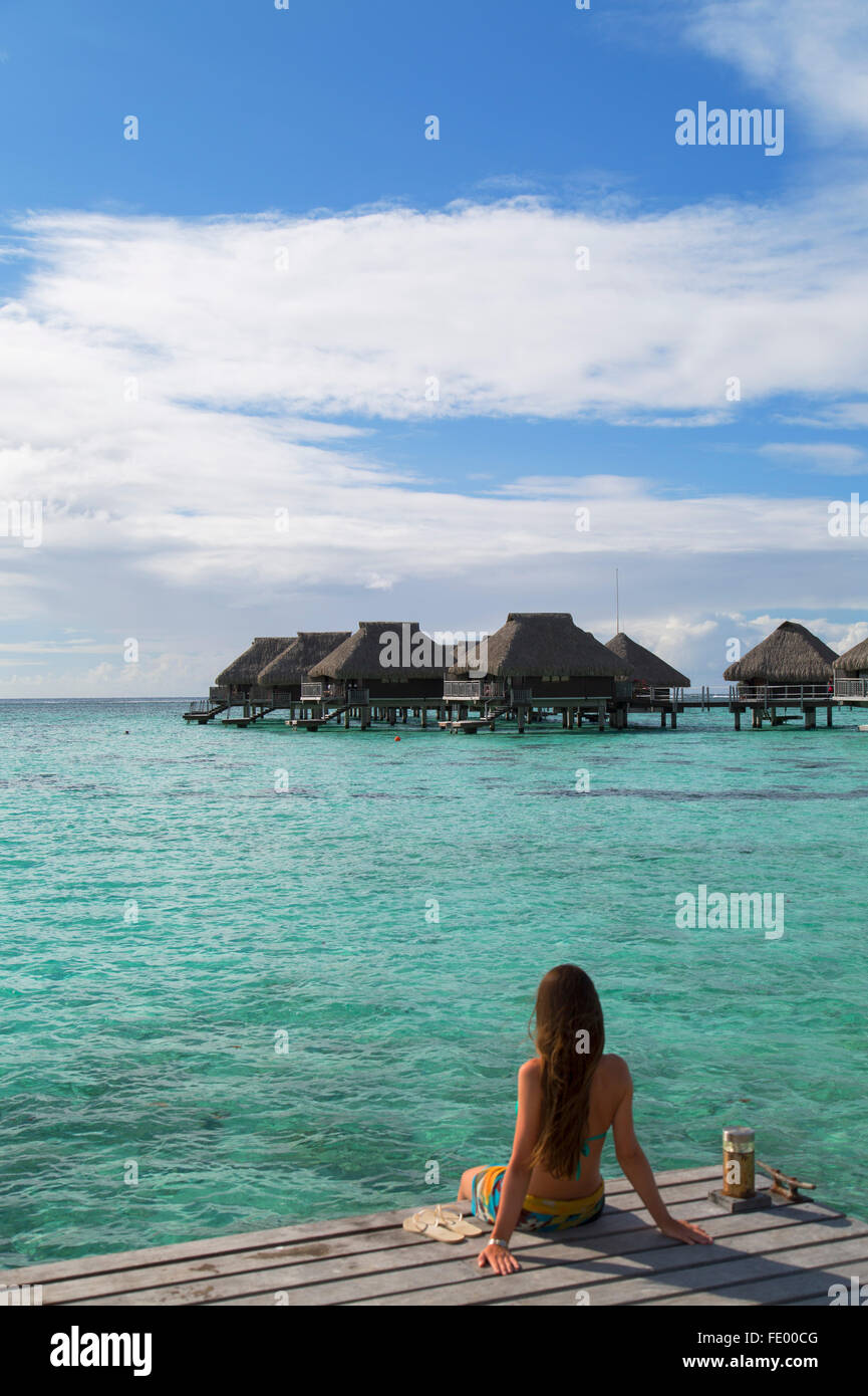 Donna seduta sul molo al Hilton Mo'orea Lagoon Resort Hotel, Moorea, Isole della Società, Polinesia Francese Foto Stock