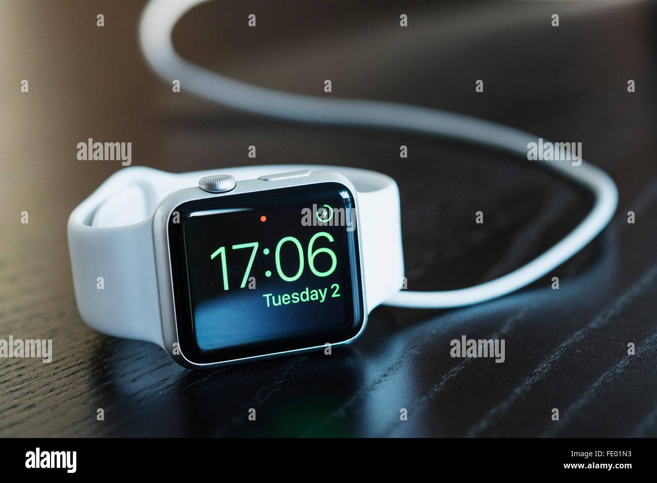 Apple orologio con cinturino bianco e di carica che mostra l'ora corrente. Foto Stock