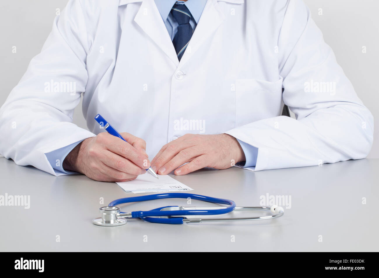 Medico nella sua sala di consultazione è in corso la scrittura di una prescrizione sulla tabella. Foto Stock