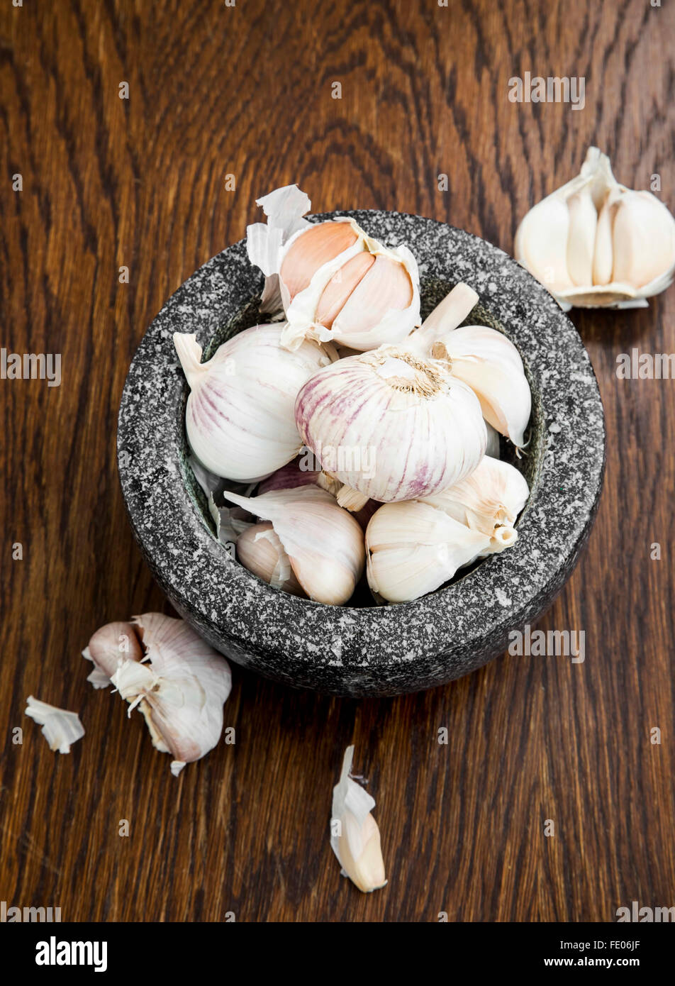 Teste d'aglio in un mortaio di marmo sul tavolo di legno Foto Stock