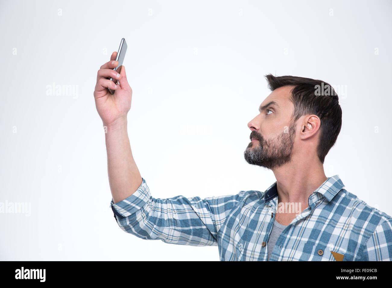 Uomo informale ricerca connessione sul telefono o rendendo selfie foto sullo smartphone isolato su uno sfondo bianco Foto Stock
