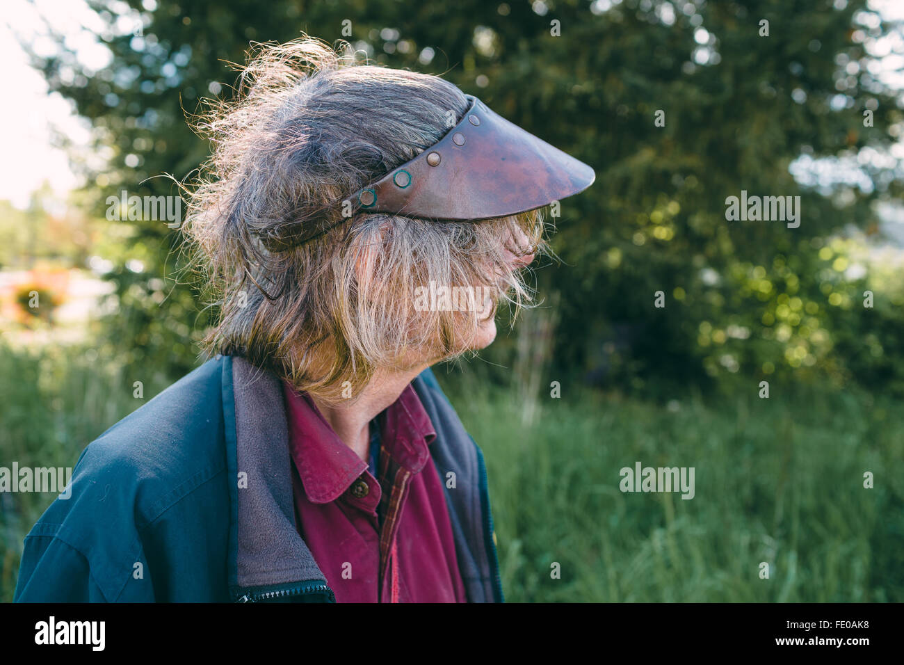 Ritratto di un vecchio uomo che indossa un cappello con un aspetto curioso sul suo volto. Capelli lunghi sull'uomo e luce naturale a mantenere questo co Foto Stock