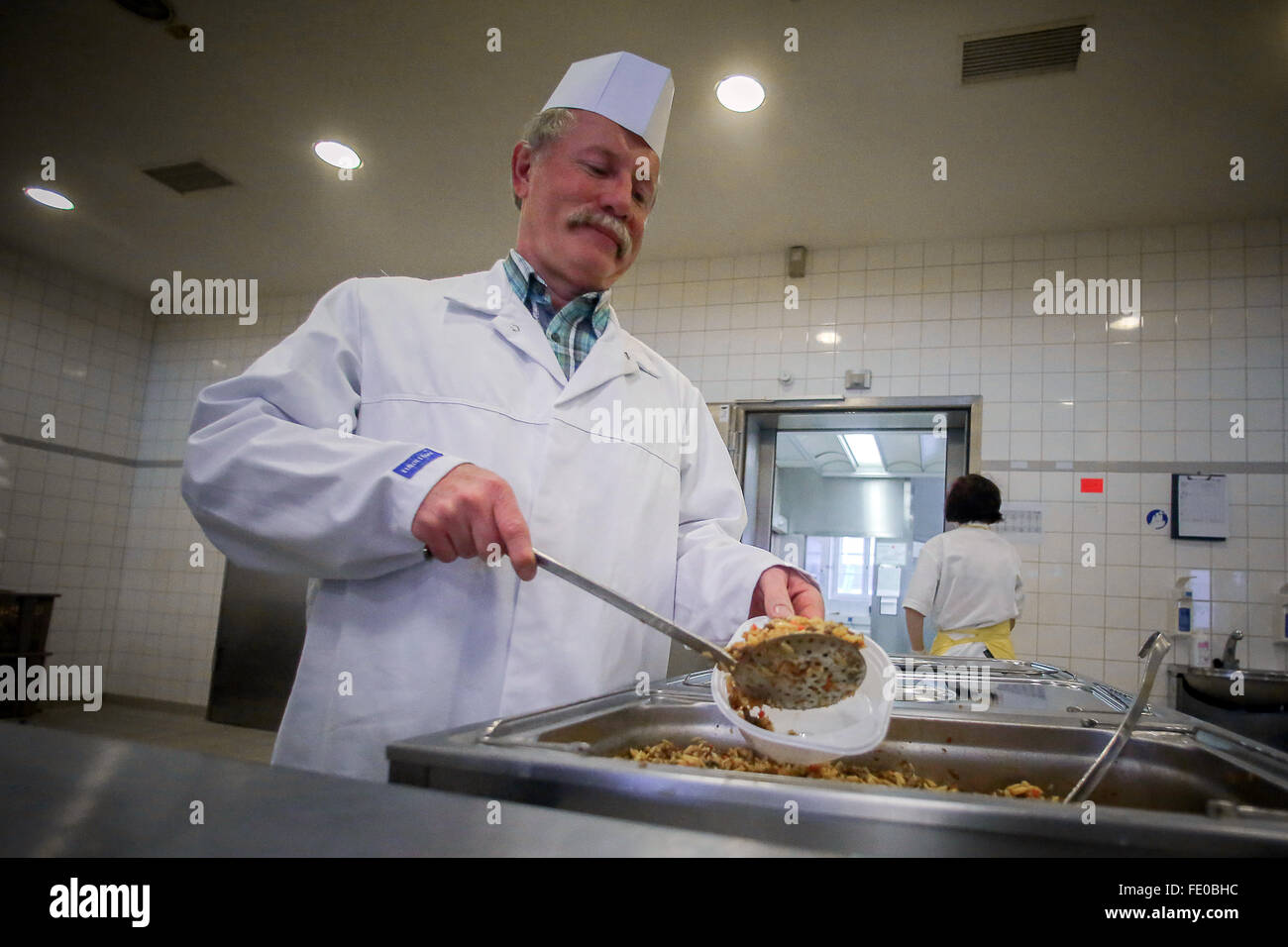 Emmerzhausen, Germania. 3 febbraio, 2016. Cuocere Alexander Doerig che serve cibo in mensa al Stegskopf richiedente asilo a centro di accoglienza in Emmerzhausen, Germania, il 3 febbraio 2016. Foto: FREDRIK VON ERICHSEN/DPA/Alamy Live News Foto Stock