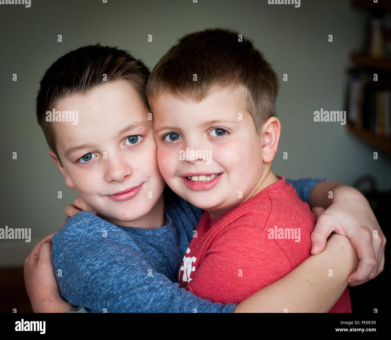 2 fratelli di 9 e 12 anni abbracciano e sorridono Foto Stock