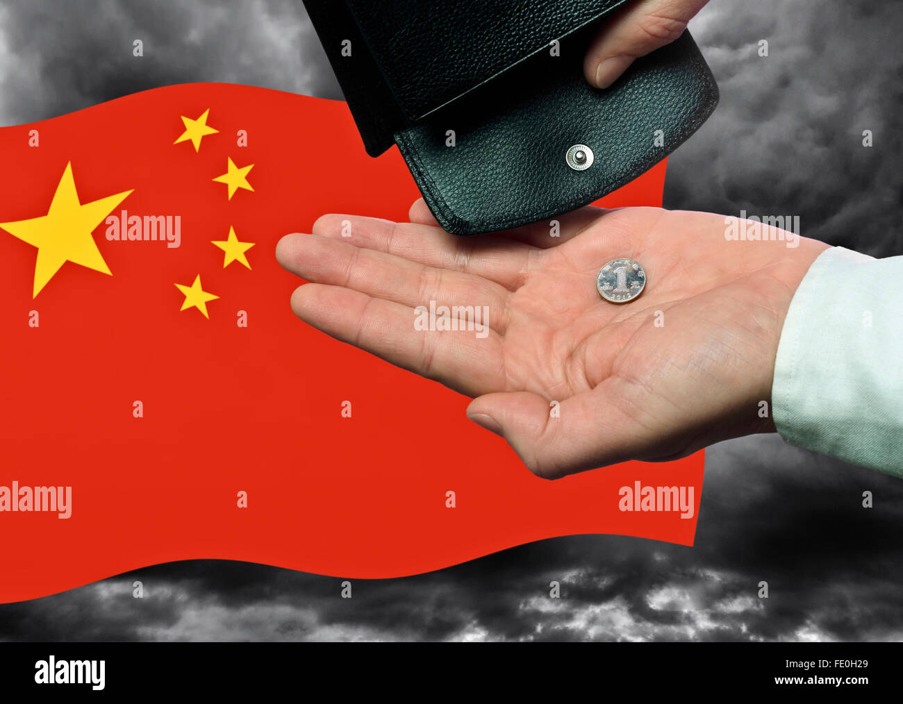 Mano con una moneta yuan bandiera cinese e portafoglio di fronte a un cielo scuro. Foto Stock