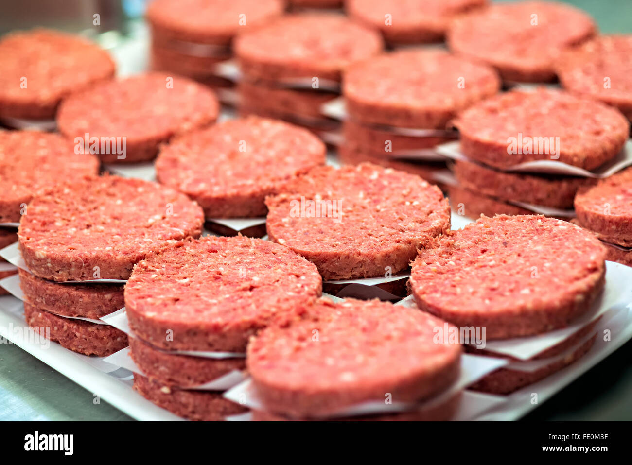 Più pile di appena raw elaborati polpette di hamburger sul display in impianto per la trasformazione di carni Foto Stock