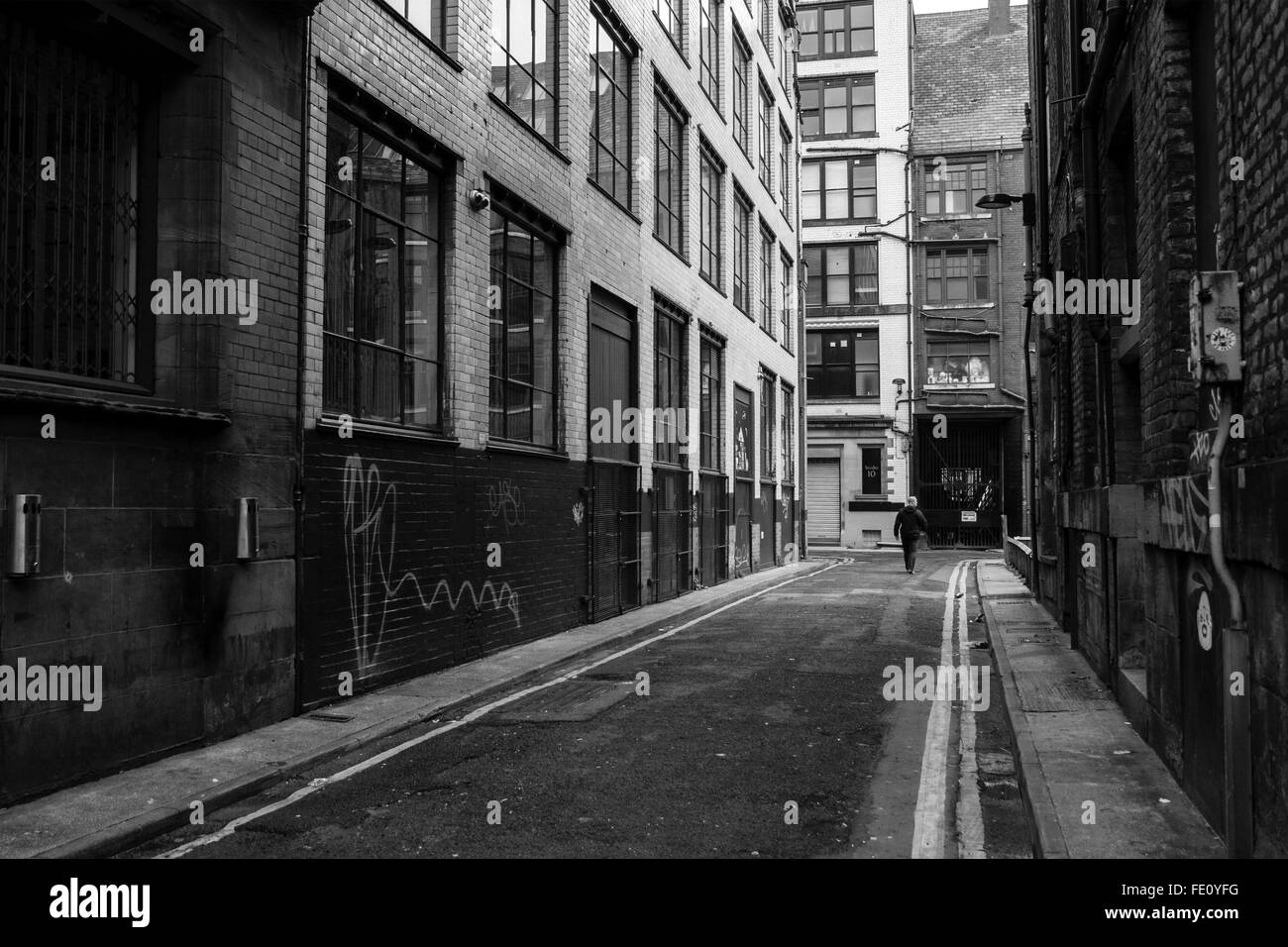 Bianco e Nero colpo di uomo a camminare su una strada posteriore in Manchester Foto Stock