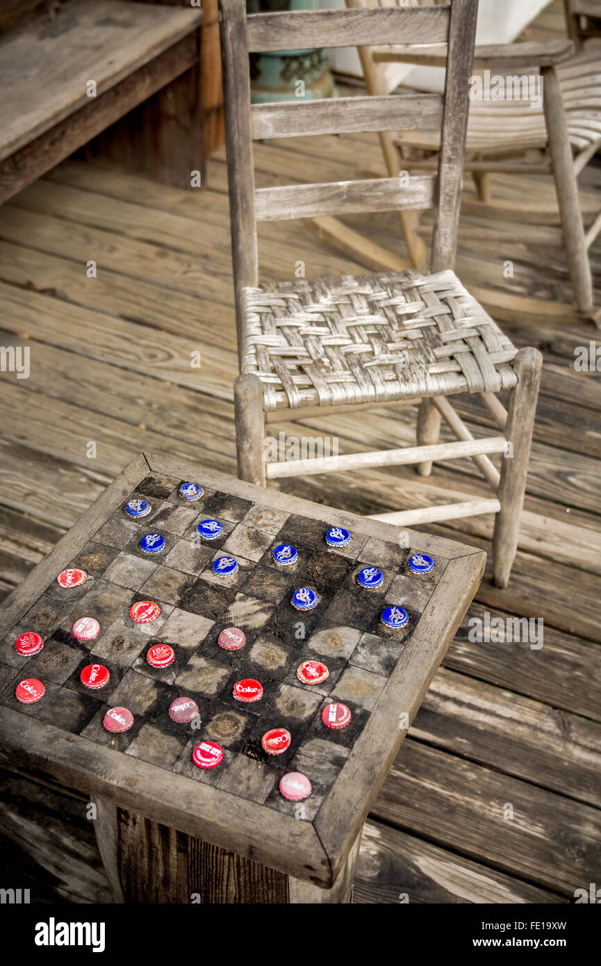 Checkers realizzato dal vecchio soft drink i tappi di bottiglia. Un vecchio veranda in legno con un vecchio rickity sedia. Foto Stock