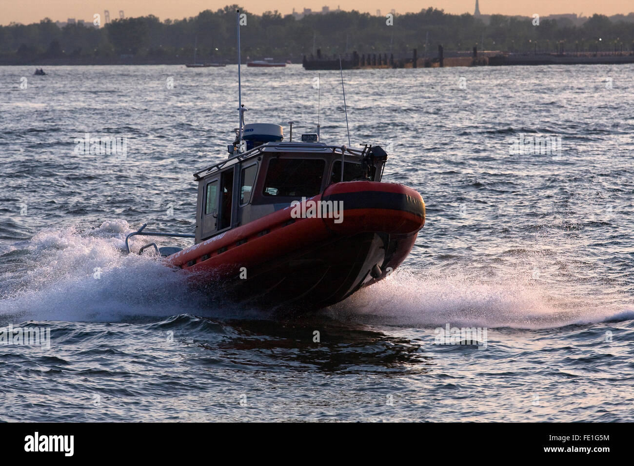 25' difensore classe US Coast Guard RB-S imbarcazione di pattuglia salta sopra un'onda sul Fiume Hudson nella città di New York al crepuscolo Foto Stock