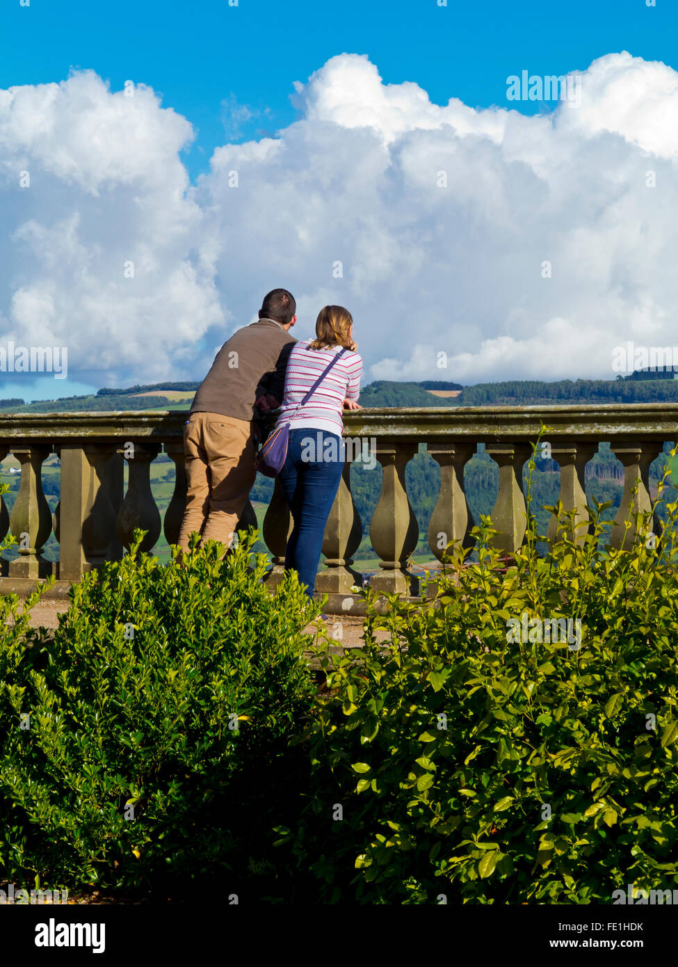 Giovane appoggiato su di una balaustra in pietra e godendo della vista sulla campagna Foto Stock