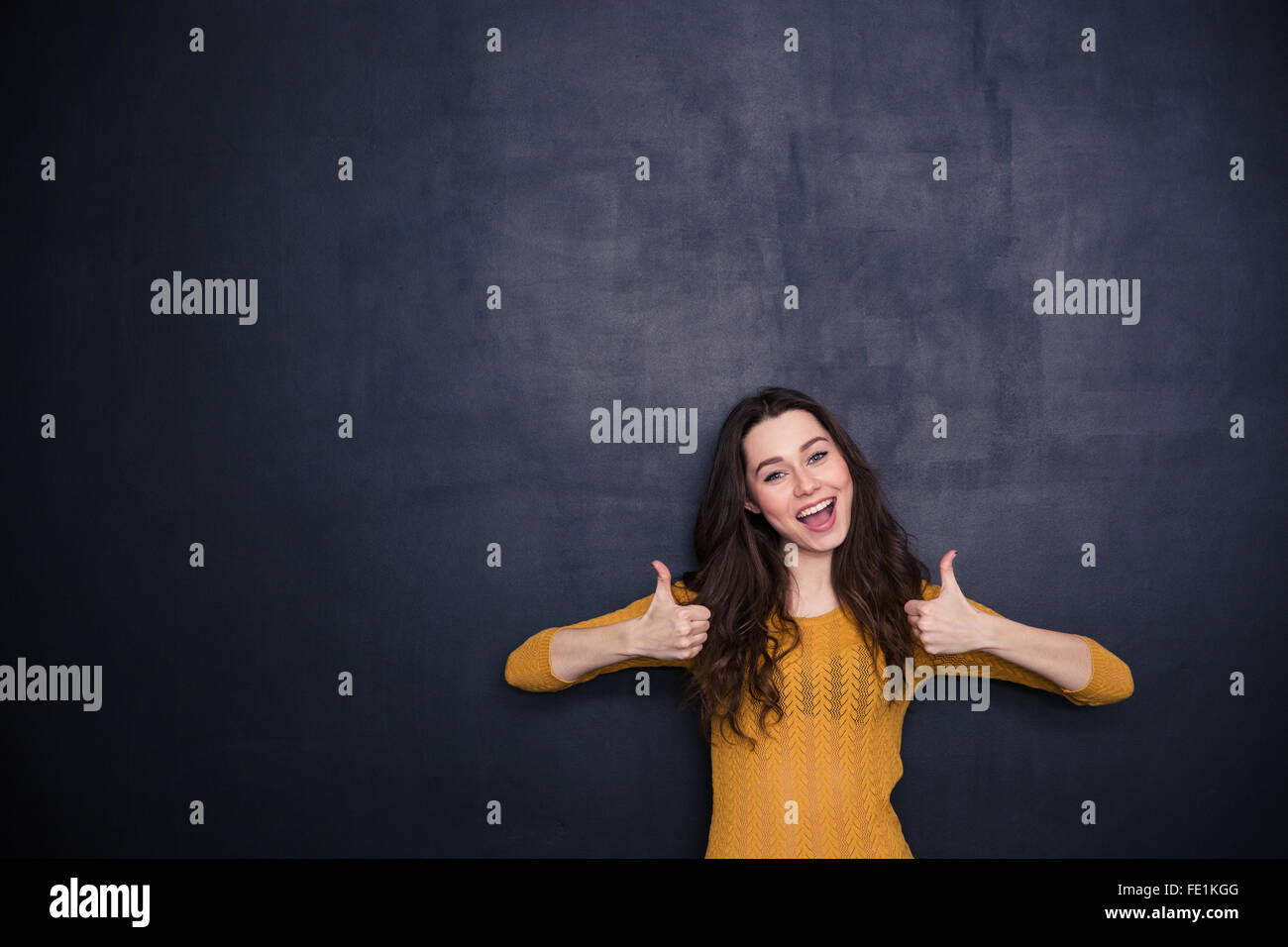 Donna allegra mostra Thumbs up su sfondo nero Foto Stock