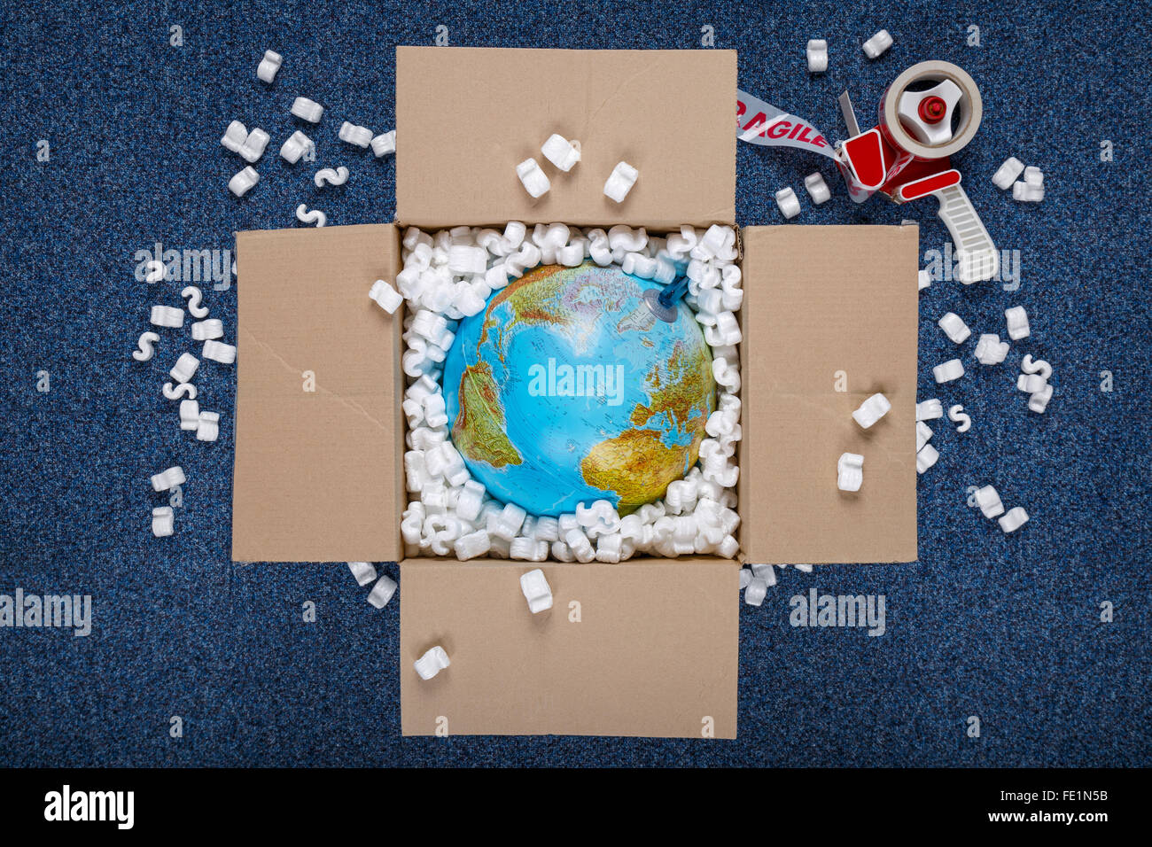 Un globo mondo in una scatola circondato da trucioli di imballaggio con nastro fragile. buona immagine per consegna internazionale concetti. Foto Stock