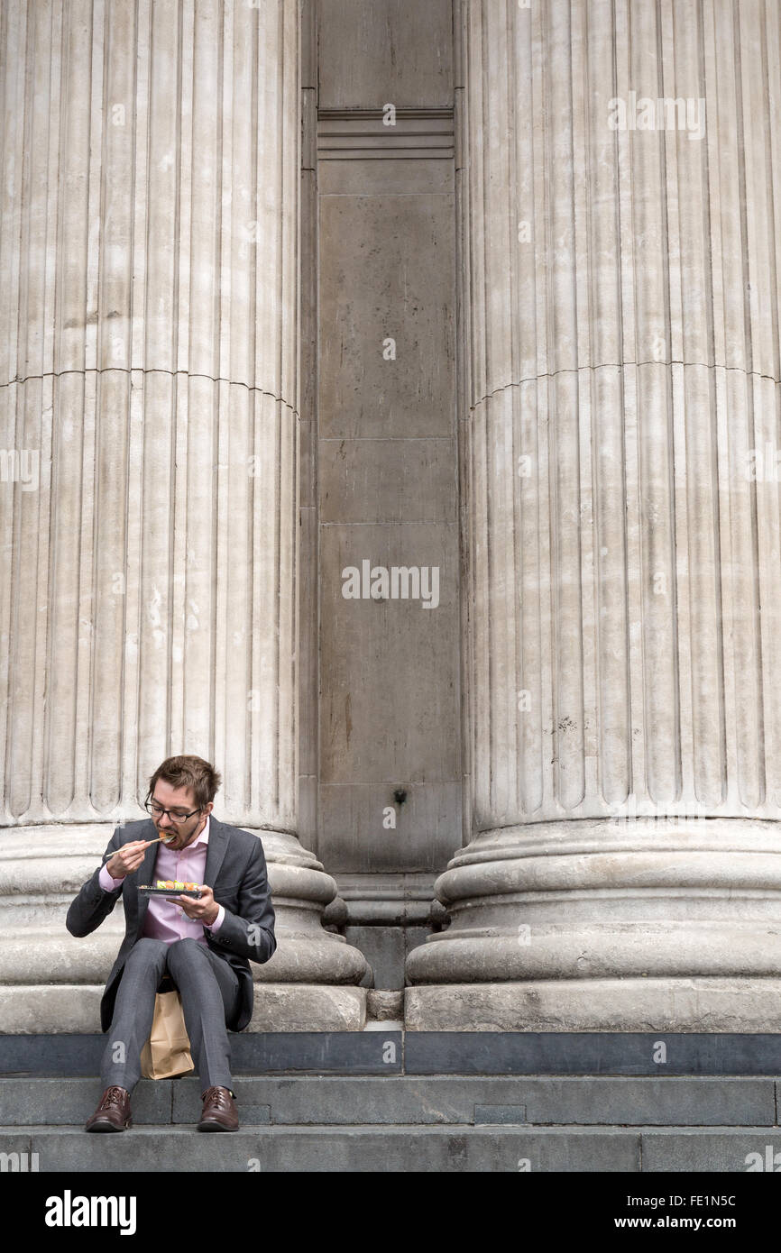 Un imprenditore sat mangiare il suo pranzo sulla scalinata della Cattedrale di San Paolo a Londra Foto Stock
