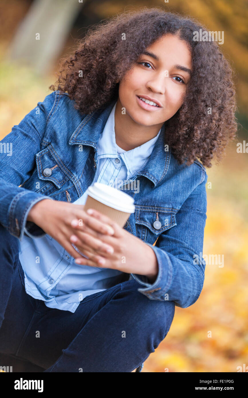 Bella felice razza mista americano africano ragazza adolescente femmine giovane donna sorridente e bere il caffè da asporto al di fuori Foto Stock