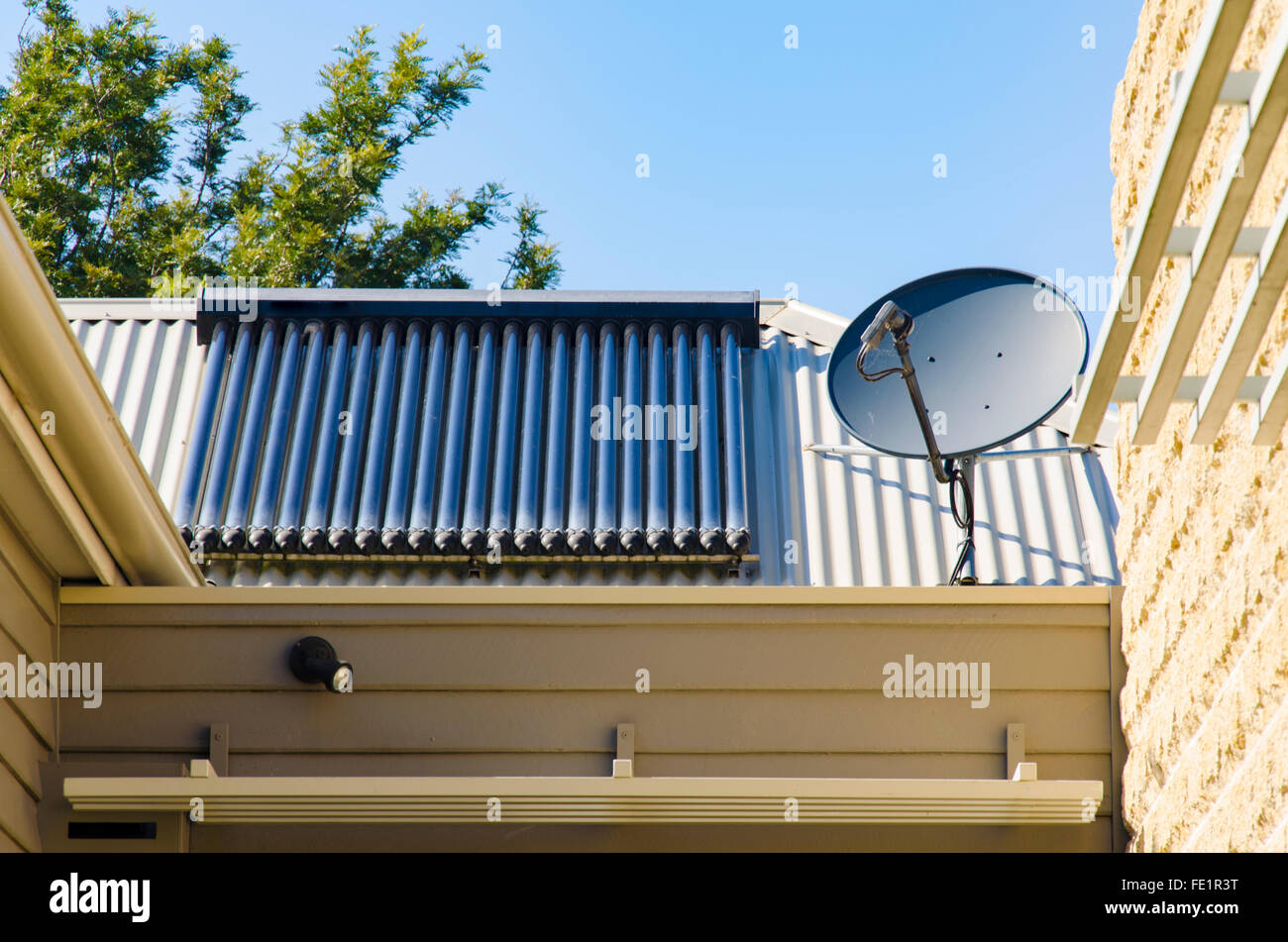 Pannelli solari ad acqua calda e parabola satellitare su un tetto in acciaio in Australia Foto Stock