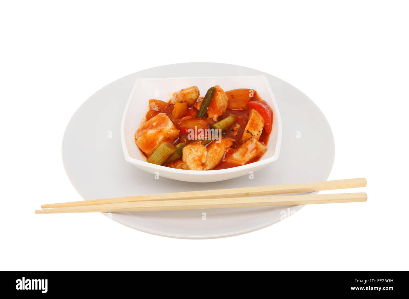 Pasto cinese, Pollo Kung Po, in una ciotola su una piastra con bacchette, isolata contro bianco Foto Stock