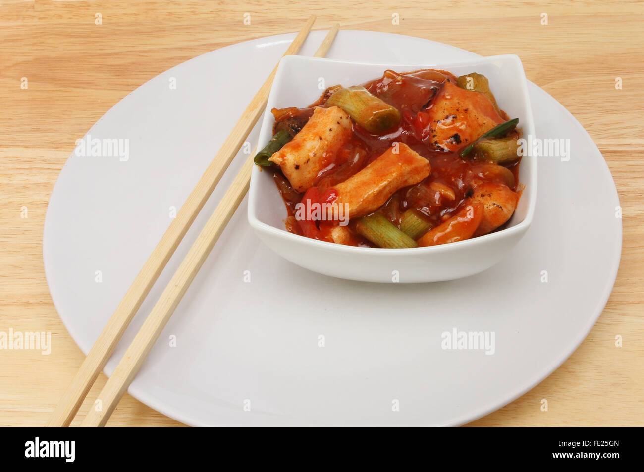 Pasto cinese, Kung Po il pollo in una ciotola su una piastra con bacchette Foto Stock
