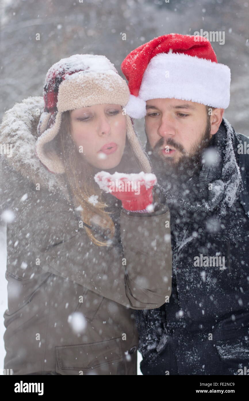 Barbuto ragazzo e ragazza piuttosto soffiando la neve dal suo lato esterno Foto Stock