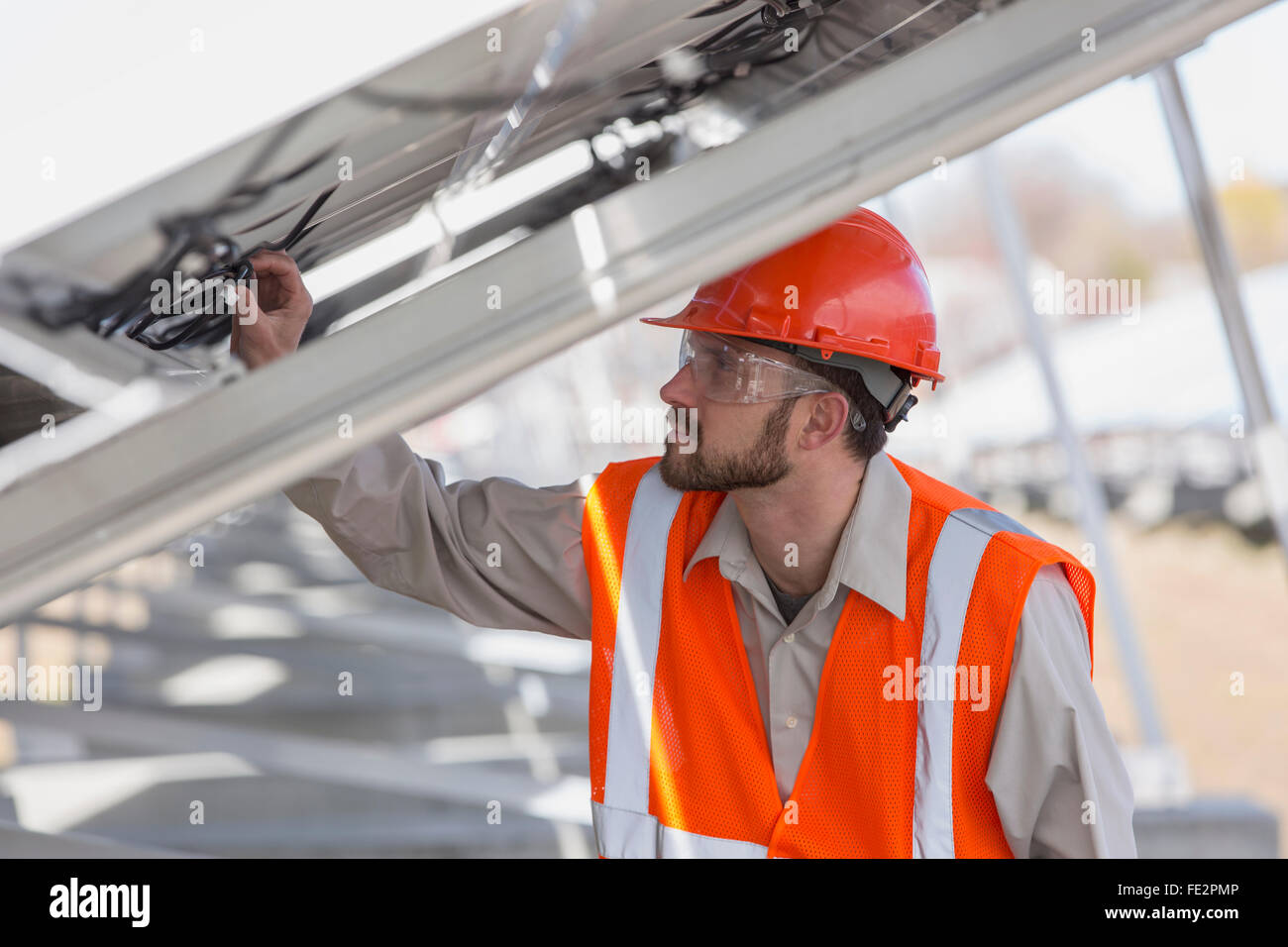 Ingegnere di alimentazione a energia solare fotovoltaica array esaminando le connessioni dei pannelli Foto Stock
