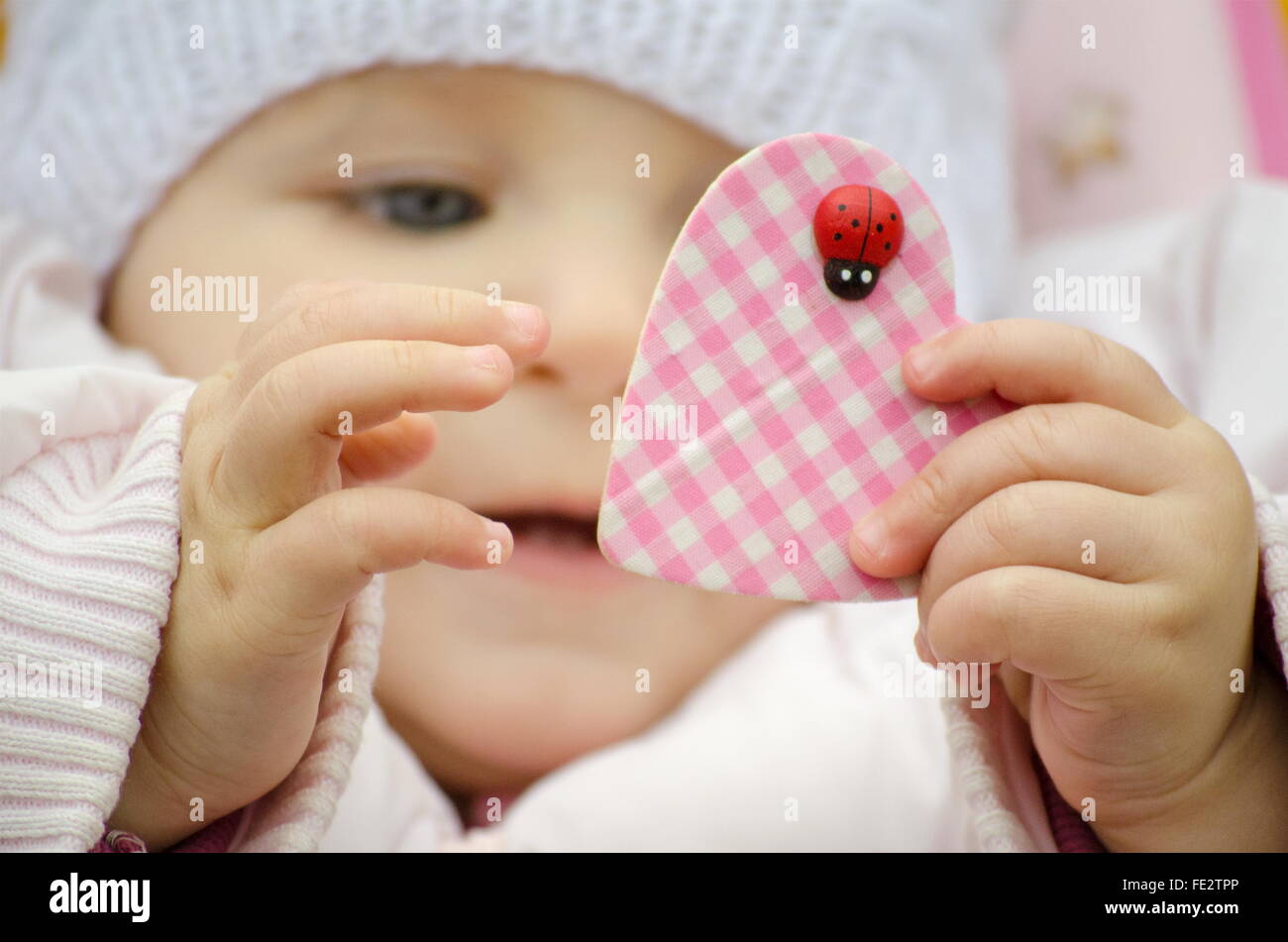 Baby indossando un cappello tenendo un cuore Foto Stock