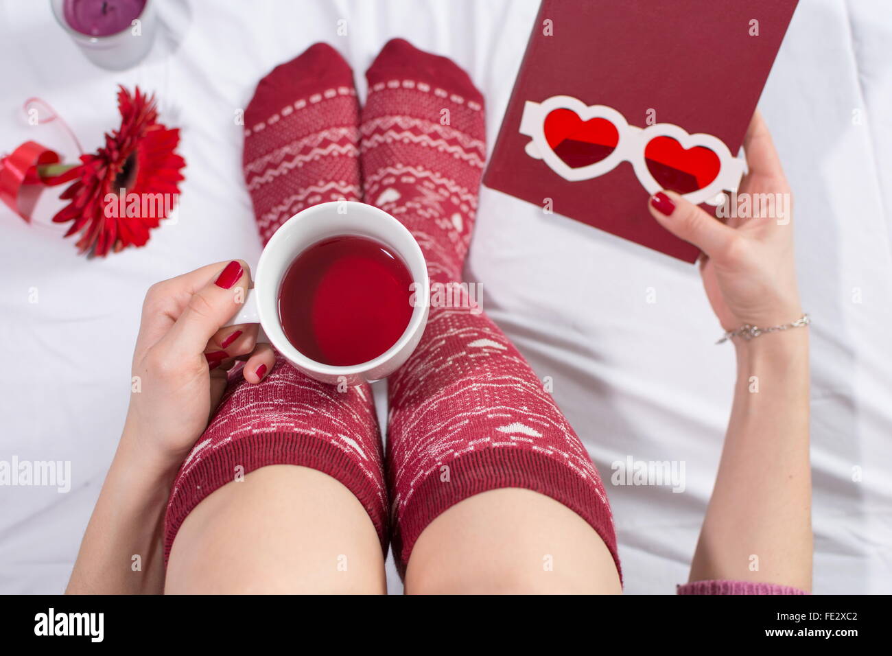 Donna con una tazza di tè nel letto e tenendo un amore nuovo Foto Stock