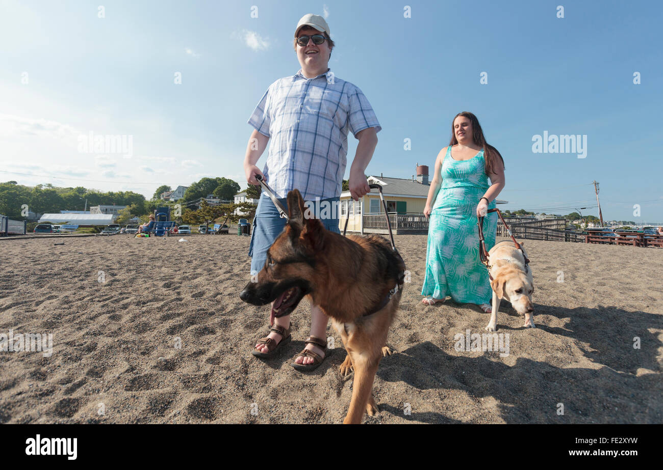 Cieco matura con i loro cani di servizio a piedi lungo la spiaggia Foto Stock
