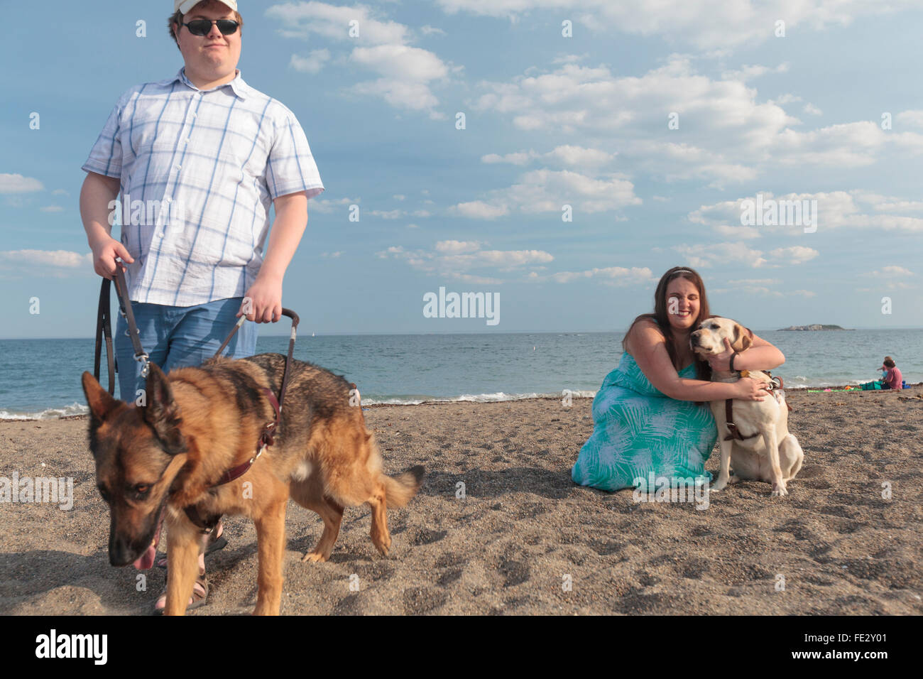 Cieco matura godendo sulla spiaggia con i loro cani di servizio Foto Stock