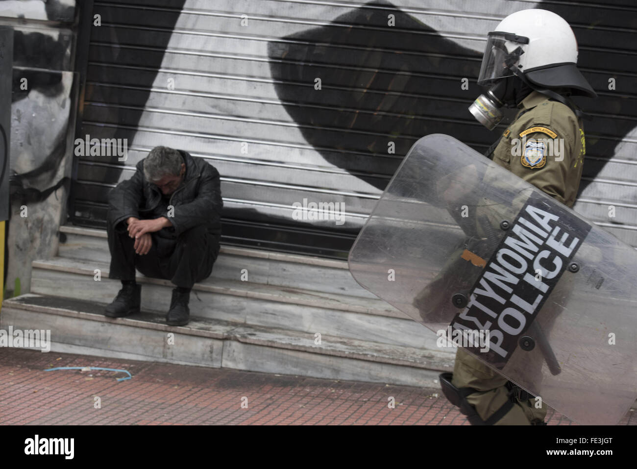 Atene, Grecia. 4 febbraio, 2016. La polizia antisommossa passano da un uomo senza tetto. Più di 50.000 persone hanno marciato per protesta per le prossime riforme della previdenza sociale. Credito: Nikolas Georgiou/ZUMA filo/Alamy Live News Foto Stock