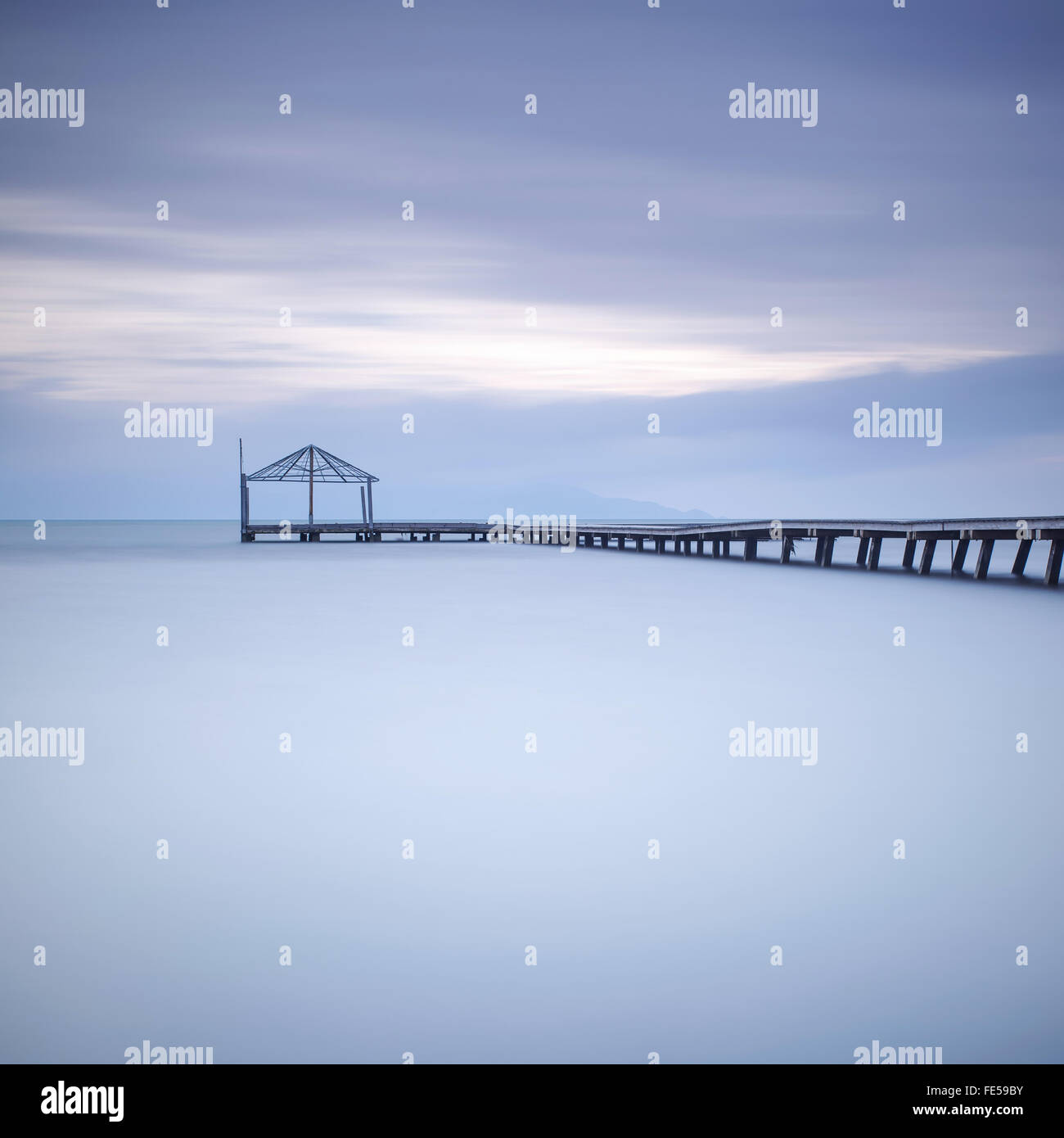 Il molo di legno o della banchina di silhouette in un oceano blu sul tramonto. Una lunga esposizione fotografie scattate in autunno in una spiaggia italiana Foto Stock