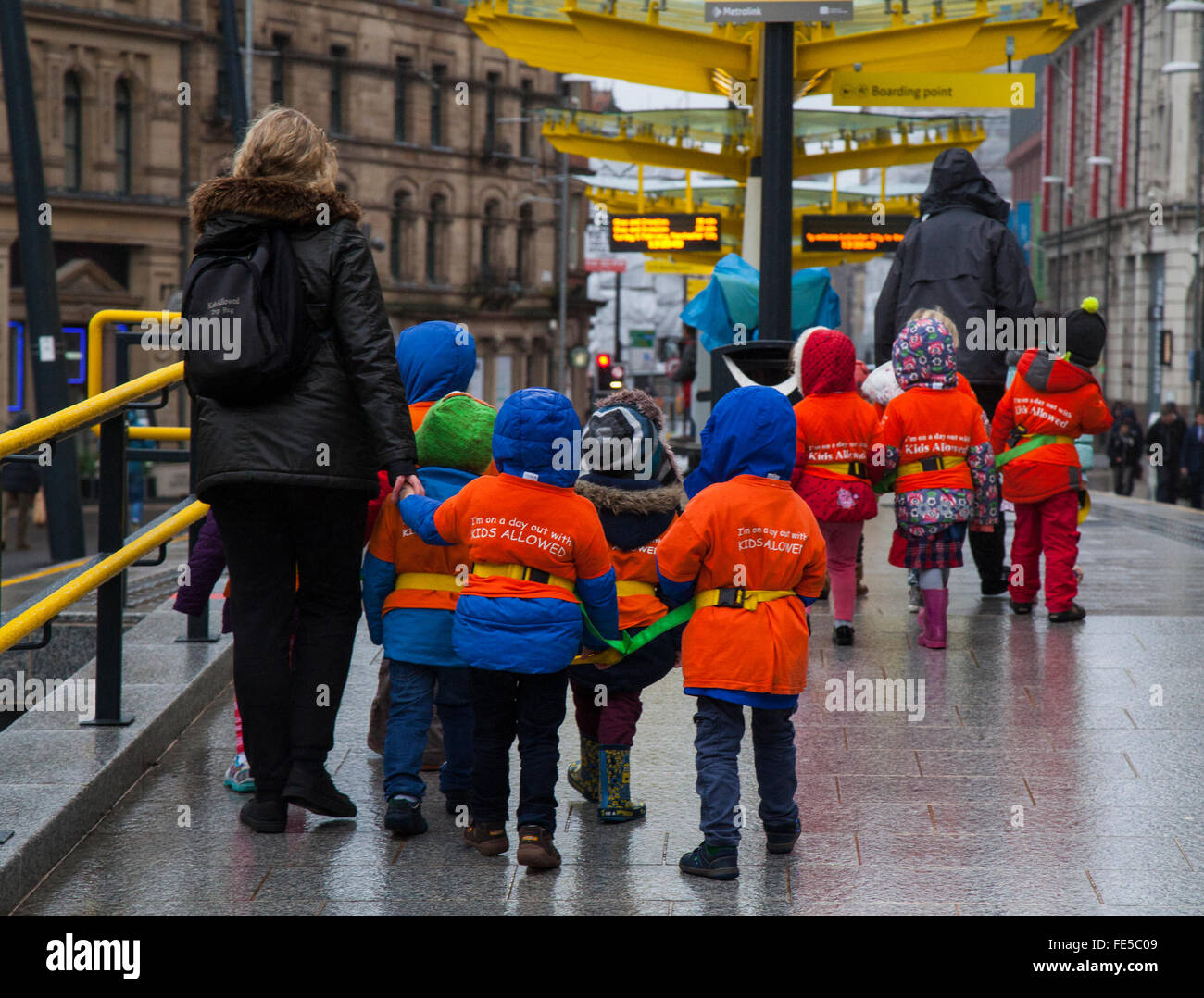 Bambini della scuola con reggetta e protezione. I bambini che camminano attraverso la strada indossando le giacche fluorescenti protettive di rischio di alta visibilità durante il Capodanno cinese, Manchester, Regno Unito. 4th Feb 2016. Gli allievi della scuola hanno collegato in una giornata fuori per vedere i preparativi per il capodanno cinese questo fine settimana. Foto Stock