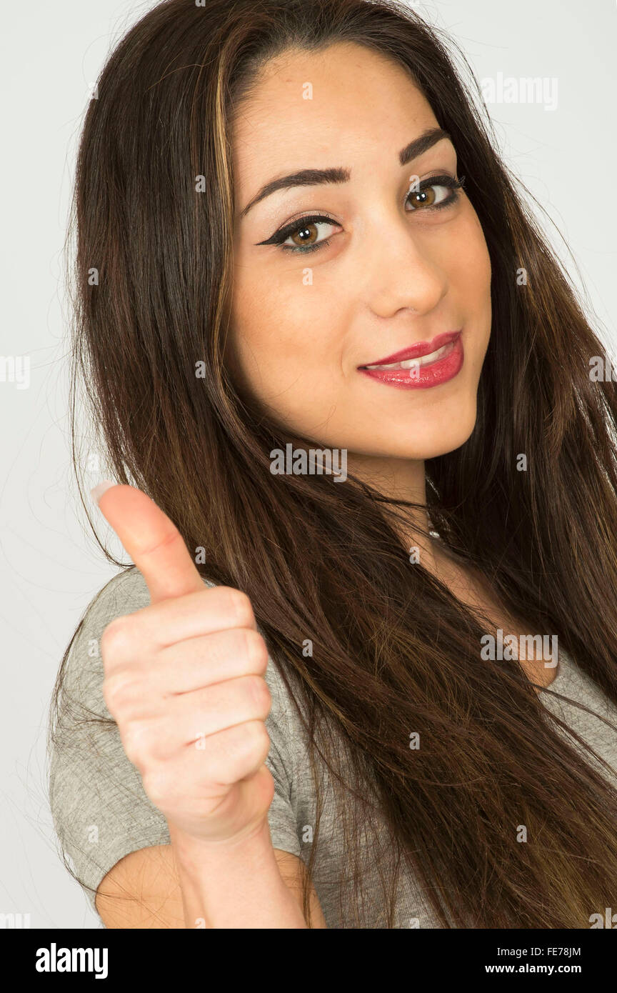 Attraente felice giovani dai capelli scuri donna sorridente dando Thumbs up gesto a mano Foto Stock