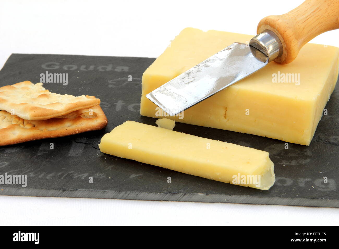 Fresche Tagliate il formaggio cheddar con cracker su una scheda di ardesia Foto Stock