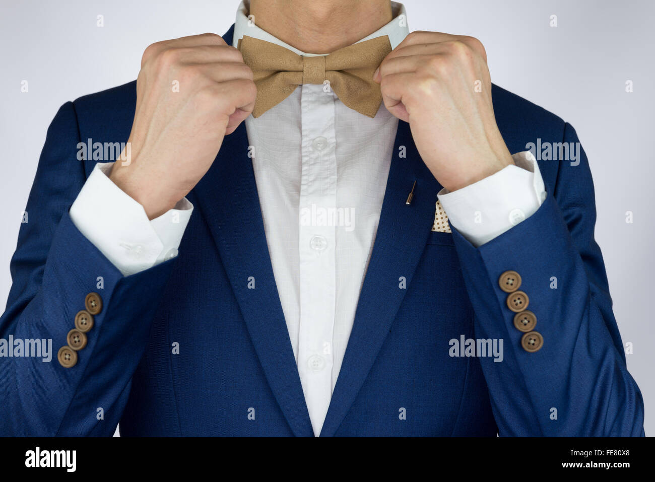 Uomo in tuta blu con crema di caffè bowtie colore, fiore spilla, e la configurazione di punti pocket Square, vicino fino Foto Stock