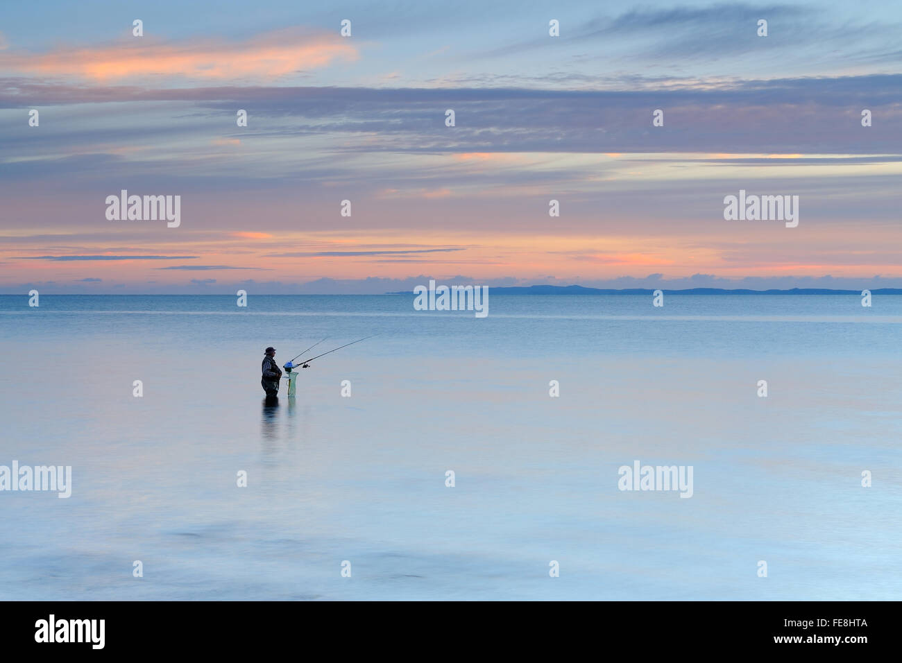 Pescatore e mare tranquillo all'alba nella baia di punto di Wellington, Queensland Foto Stock