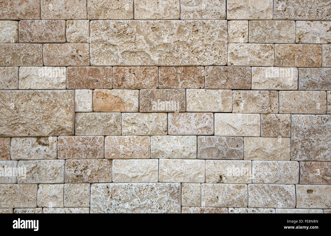 Una parte del muro di pietra naturale beige struttura porosa. Finitura della pietra rettangolare di forma e dimensioni diverse. Foto Stock