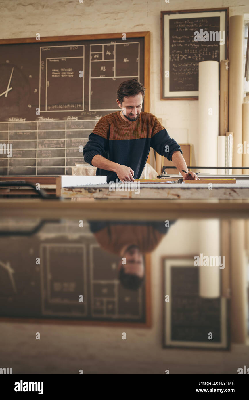 Falegname specializzato lavora con la concentrazione su un progetto nel suo studio per la lavorazione del legno Foto Stock
