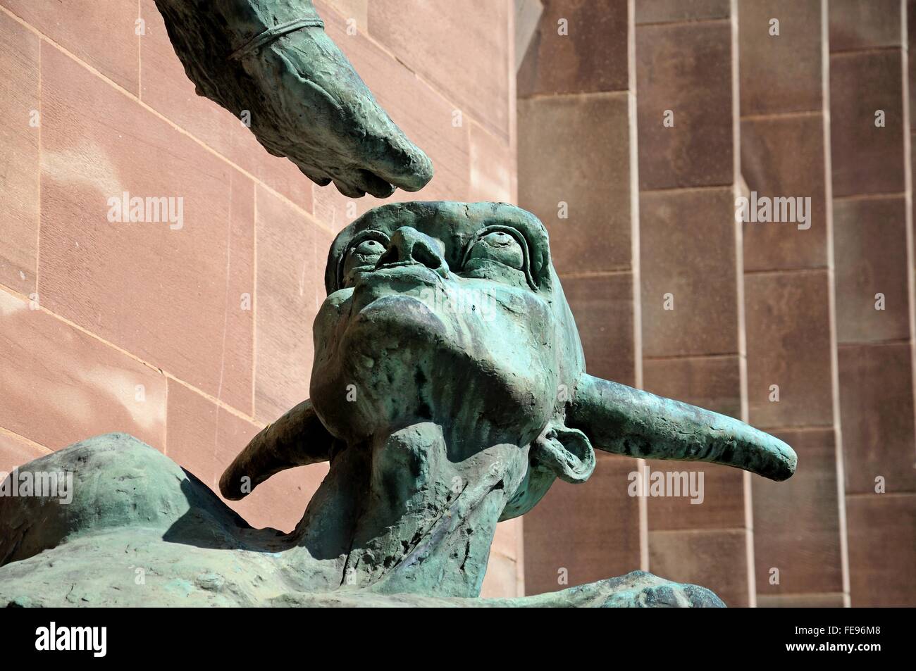La testa di diavoli sotto St Michaels piede (Michael e il diavolo) sulla parete della nuova cattedrale, Coventry, Inghilterra, Regno Unito. Foto Stock