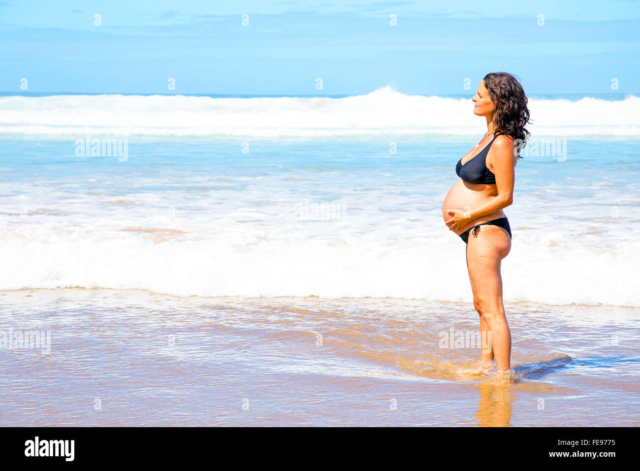 Bella donna incinta in spiaggia Foto Stock