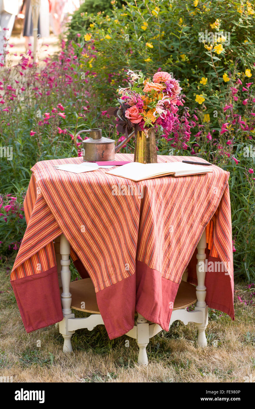 Tavolo antico con guest book e fiori nel giardino in un ambiente informale all'aperto in stile country matrimonio. Bella shabby chic estate decorazioni per matrimoni. Foto Stock