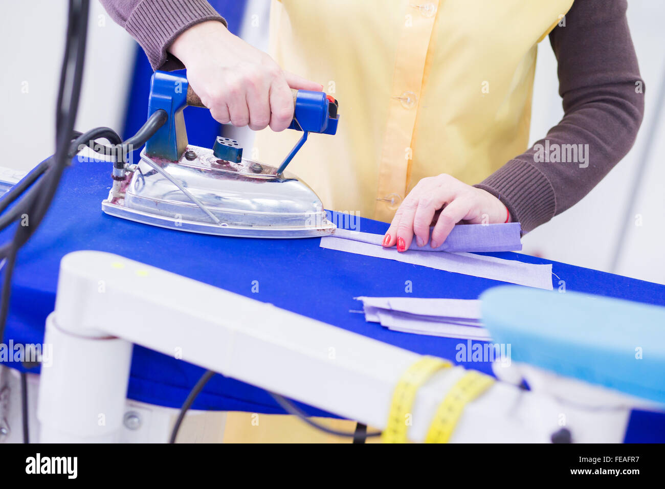 La donna la stiratura di panni al lavoro Foto Stock