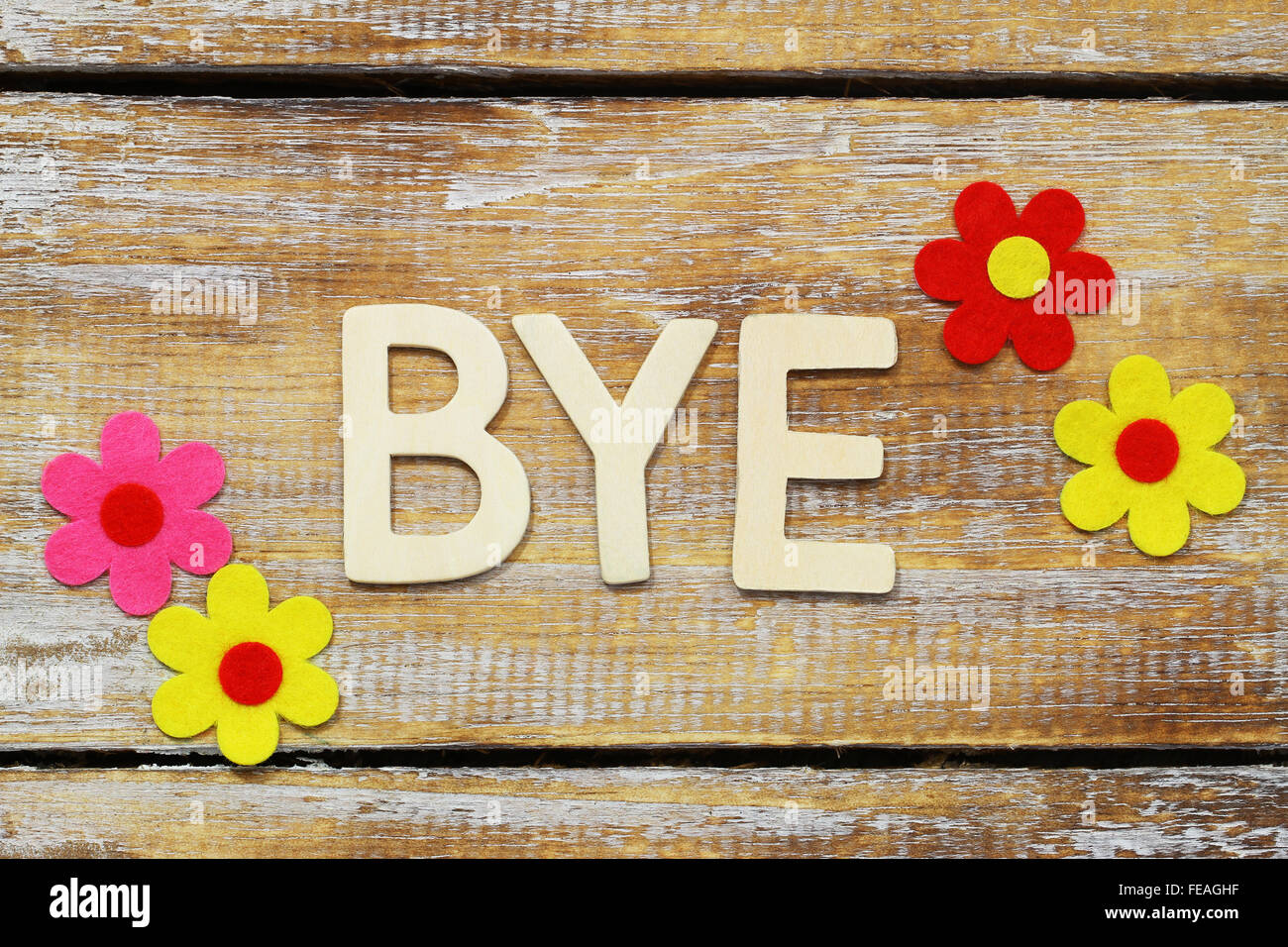 Parola bye scritto con lettere di legno sulla superficie di rustico e fiori colorati Foto Stock