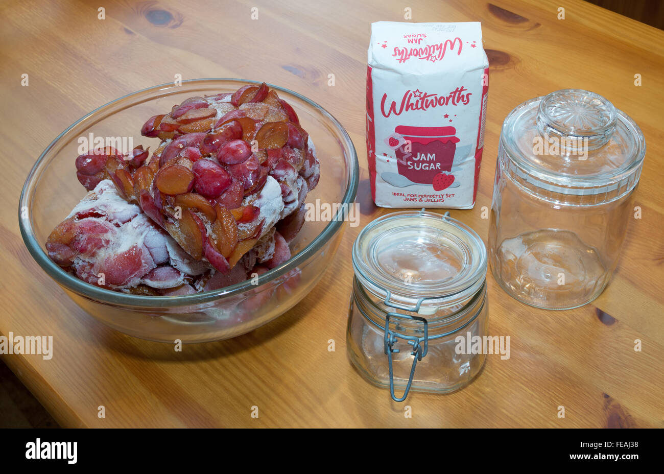 Confettura di prugne rendendo ingredienti, lo sbrinamento di prugne, confettura Whitworths zucchero e barattoli per conserve. Foto Stock