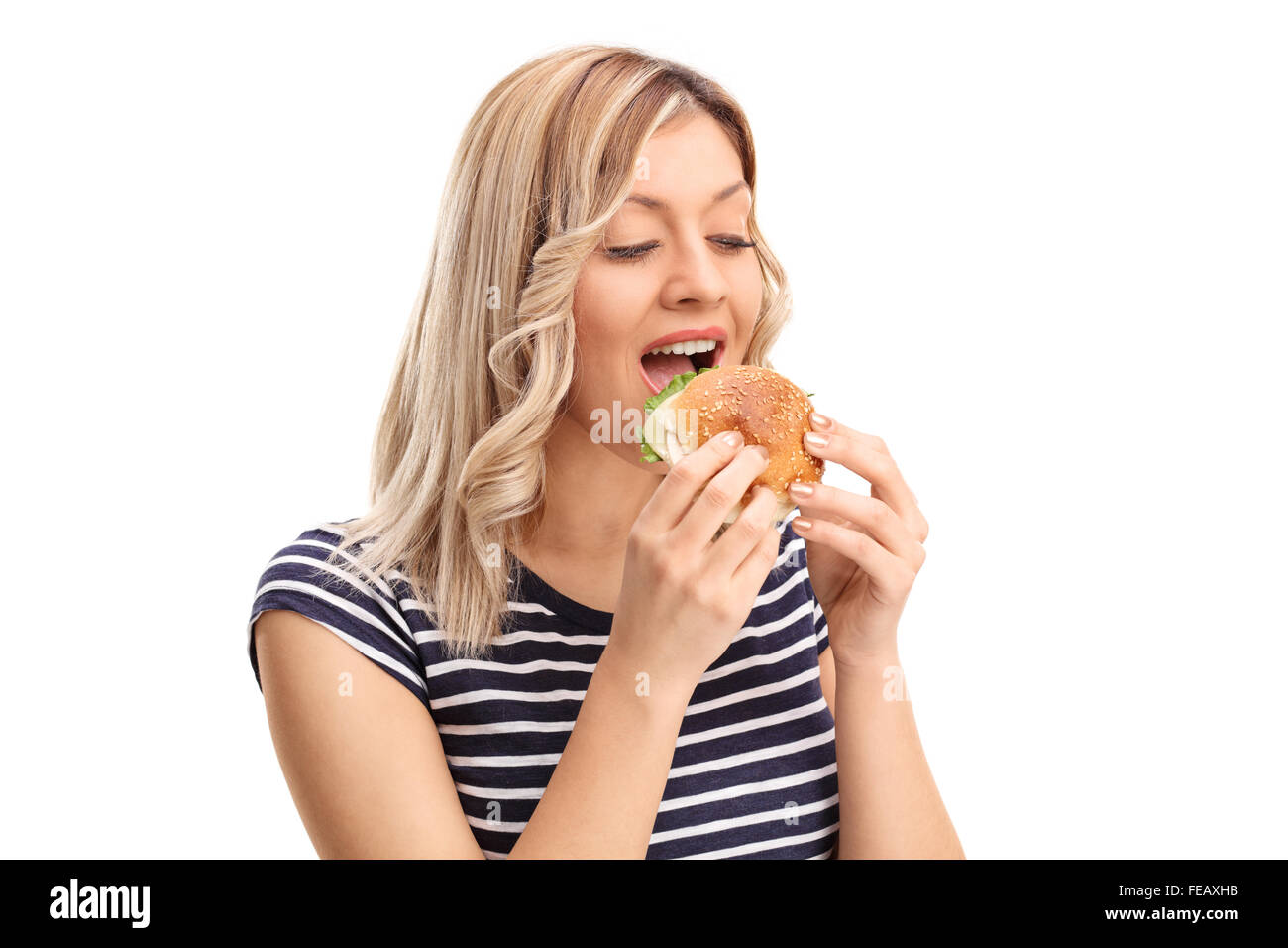 Studio shot di una gioiosa giovane donna di mangiare un panino isolati su sfondo bianco Foto Stock
