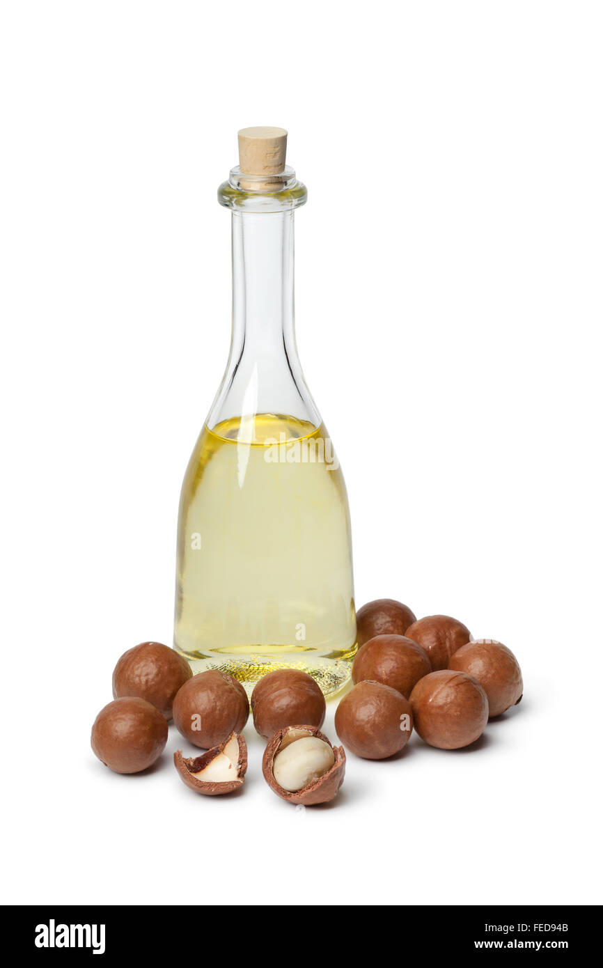 Bottiglia con olio di macadamia e i dadi su sfondo bianco Foto Stock