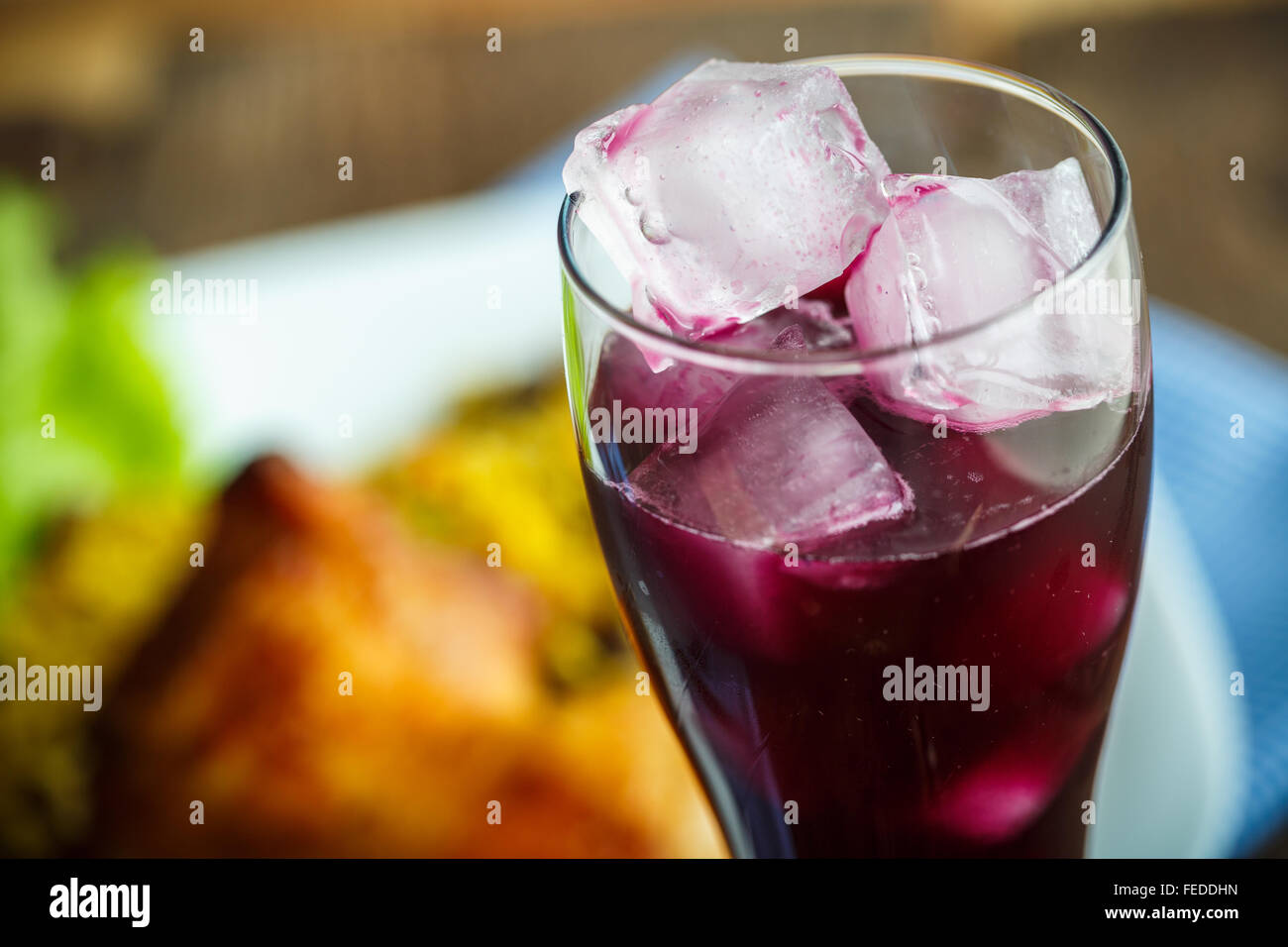 Piatti deliziosi da coscia di pollo con riso e lattuga e un bicchiere di succo di frutta con ghiaccio Foto Stock