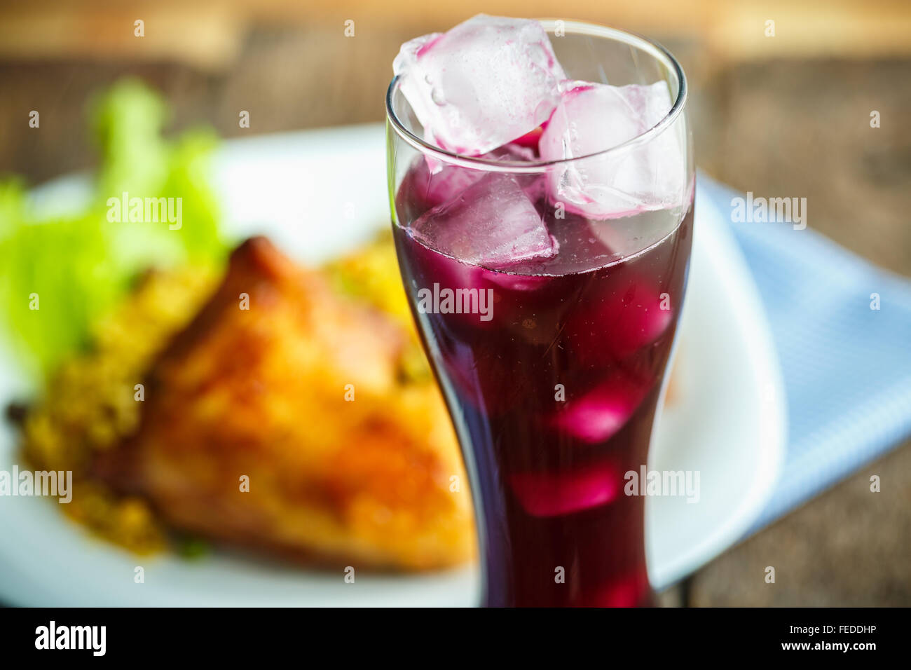 Piatti deliziosi da coscia di pollo con riso e lattuga e un bicchiere di succo di frutta con ghiaccio Foto Stock