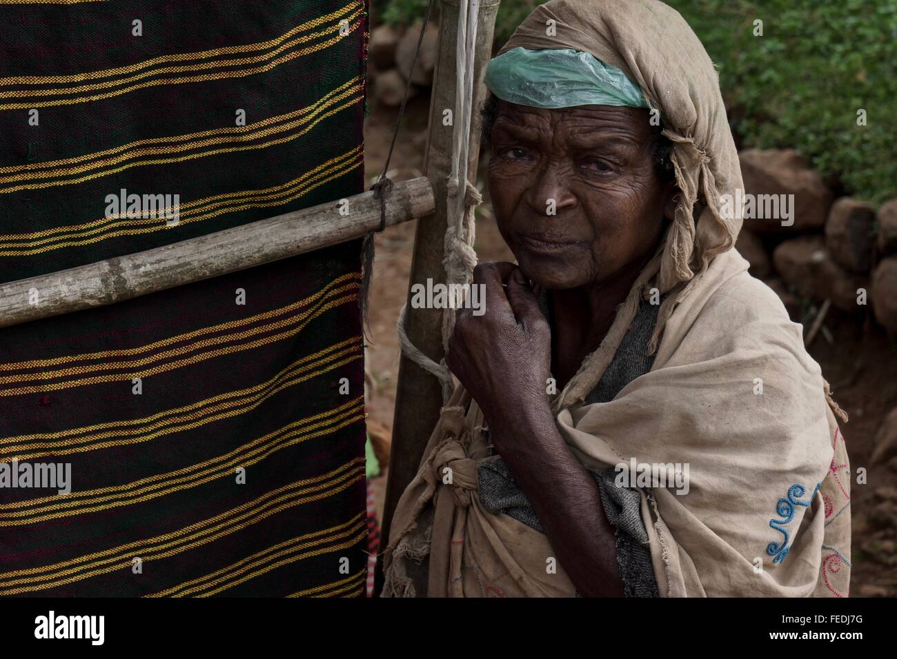 Il vecchio donna etiope accanto ai prodotti tessili. Foto Stock